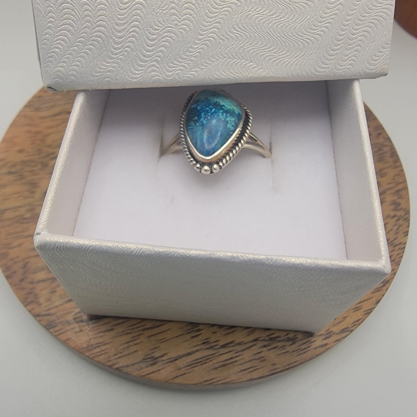 Jewelry box with a blue stone ring on a wooden surface