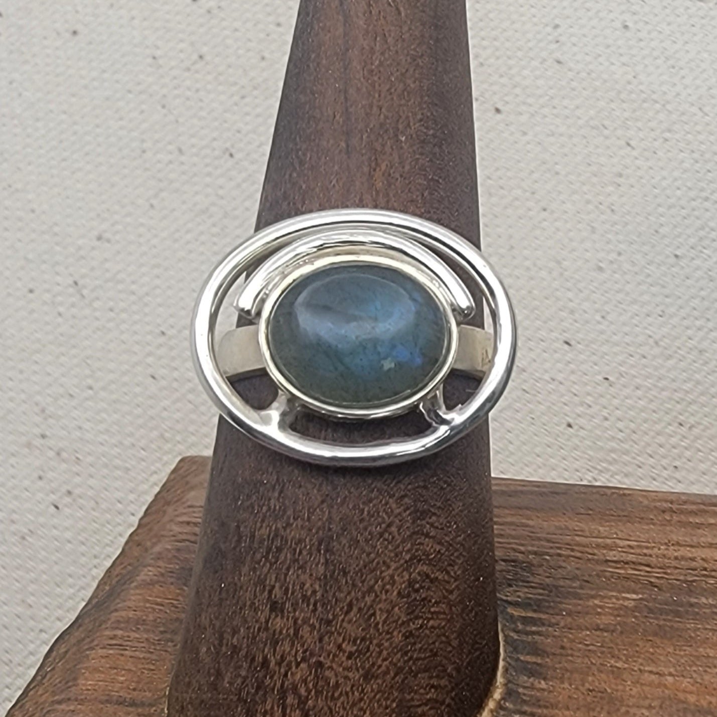 Labradorite Ring 925 Sterling Silver Statement Ring showcased on a wooden display, perfect for casual jewelry lovers. This unique design makes it an ideal Gift for Her or Gift for Him, enhancing any outfit with its elegant shine. A stunning statement ring crafted in Sterling Silver.