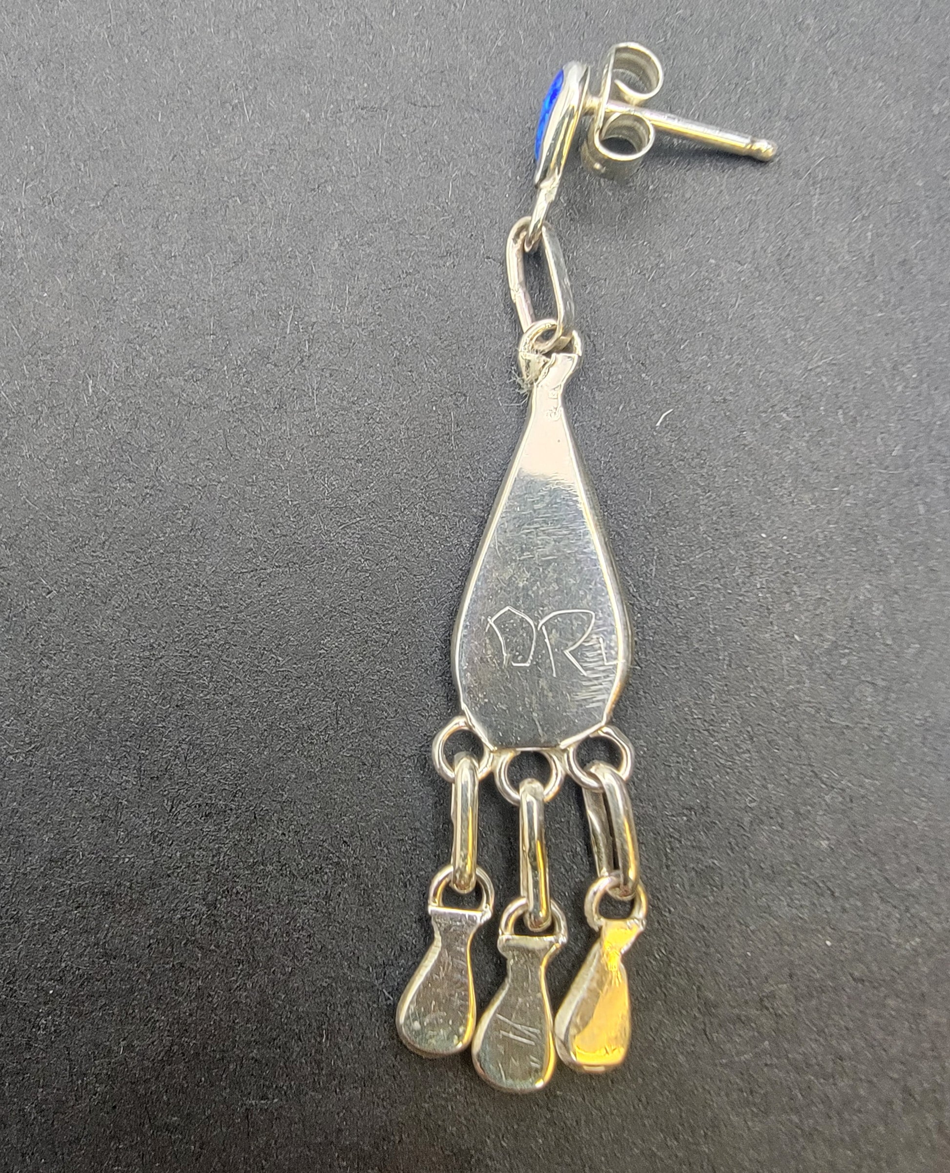 Hand crafted opal inlay dangle earrings displayed on model, demonstrating their graceful movement and elegance.