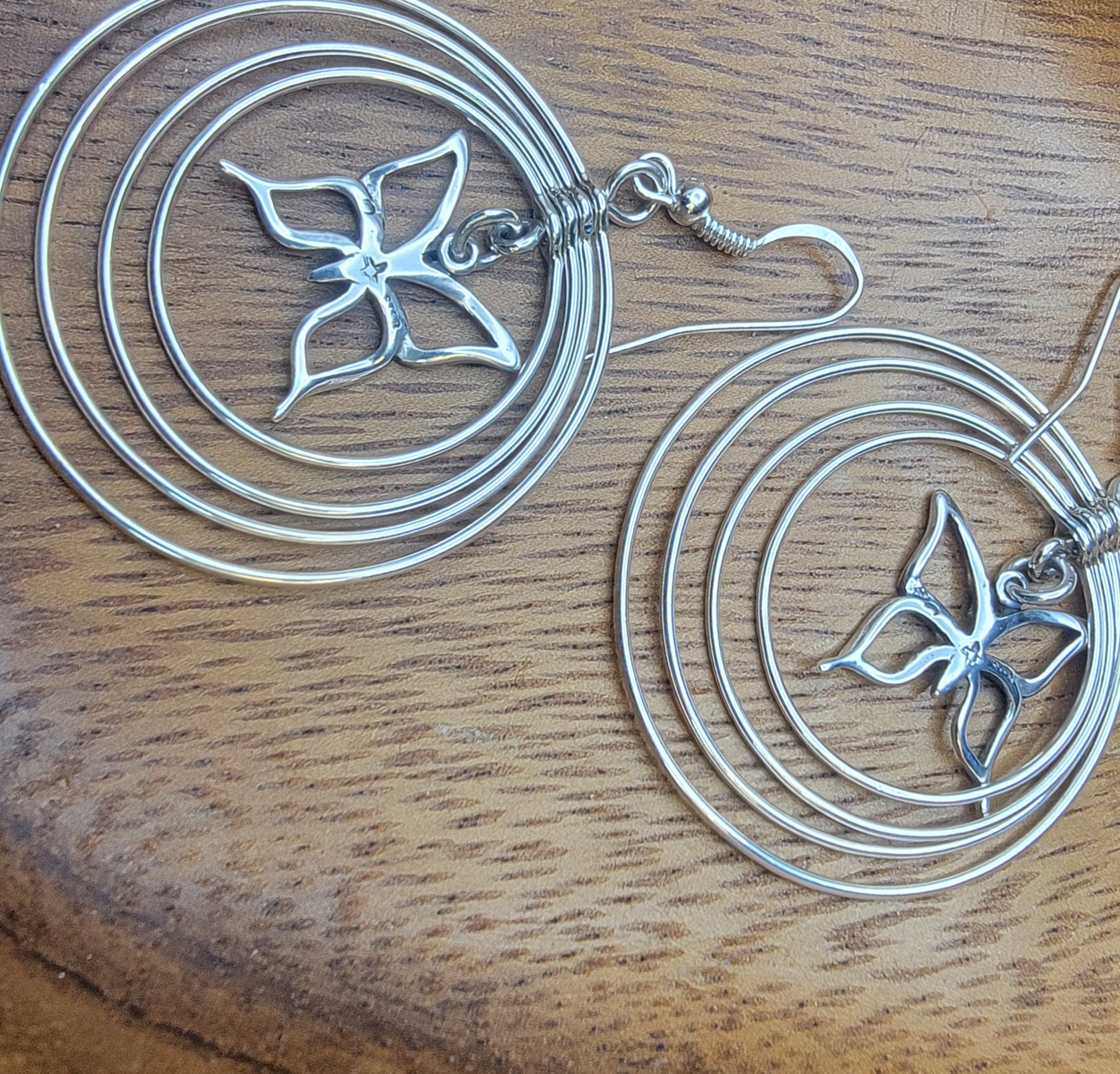 Sterling silver concentric hoop earrings (2¼″ × 1½″) featuring four graduated rings framing a delicate butterfly charm.