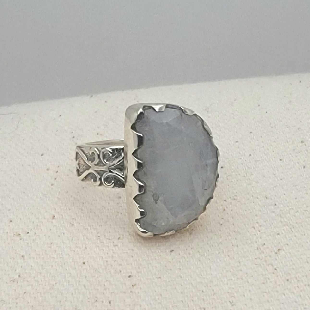Size 8.5 sterling silver ring featuring a 10×15 mm half-moon moonstone set in a scalloped bezel on a tapered band.
