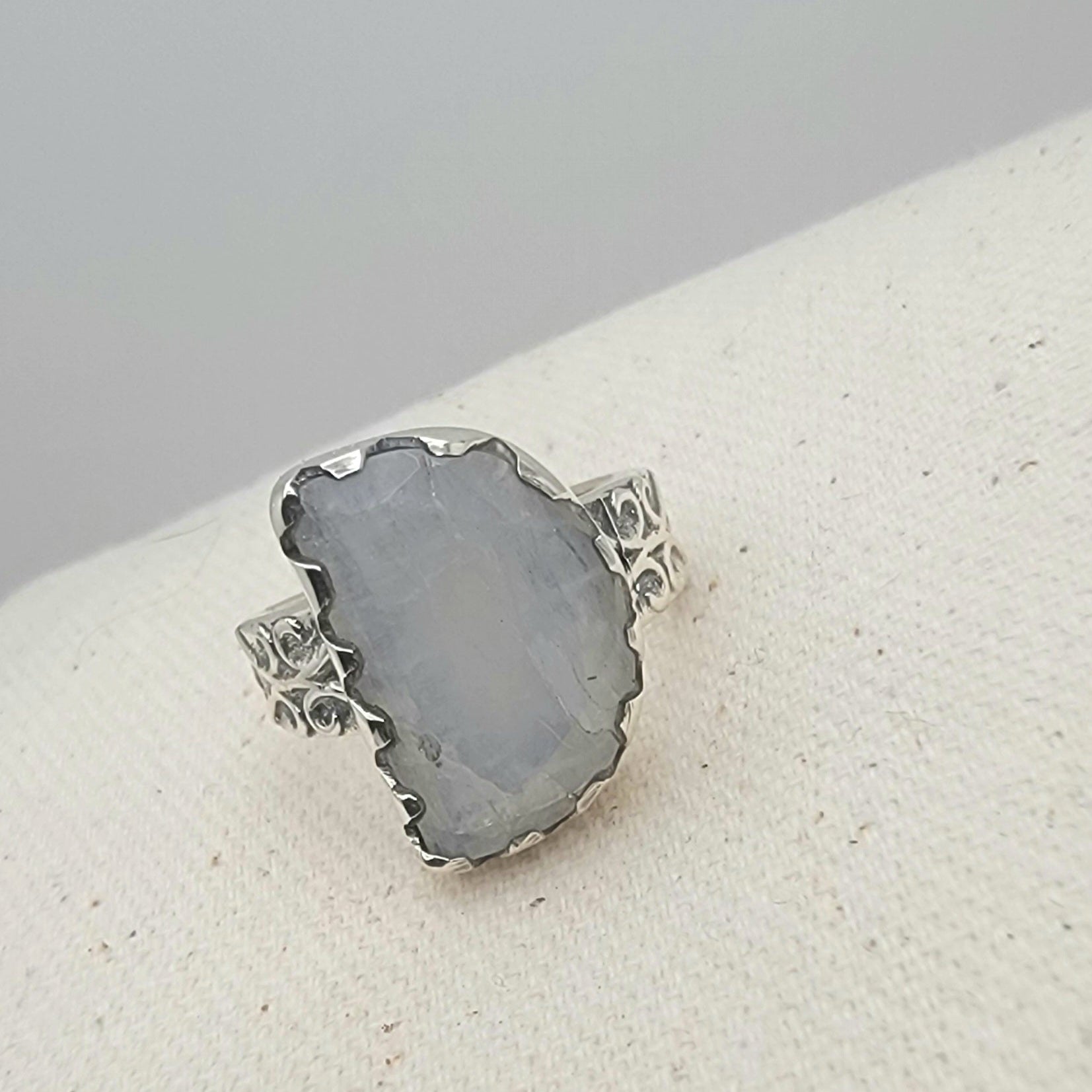 Size 8.5 sterling silver ring featuring a 10×15 mm half-moon moonstone set in a scalloped bezel on a tapered band.