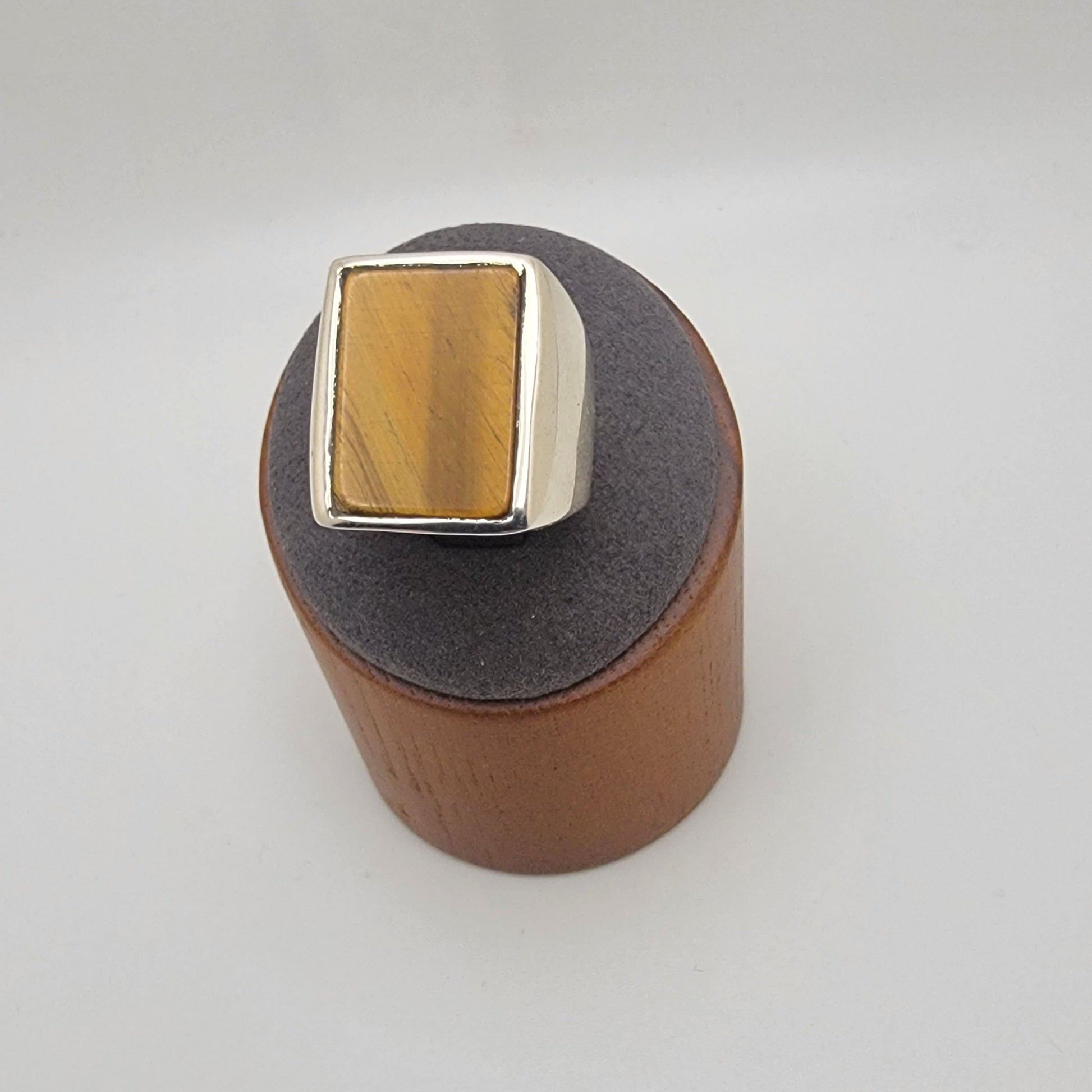 Silver ring with rectangular tiger's eye cabochon in grey and wooden stand