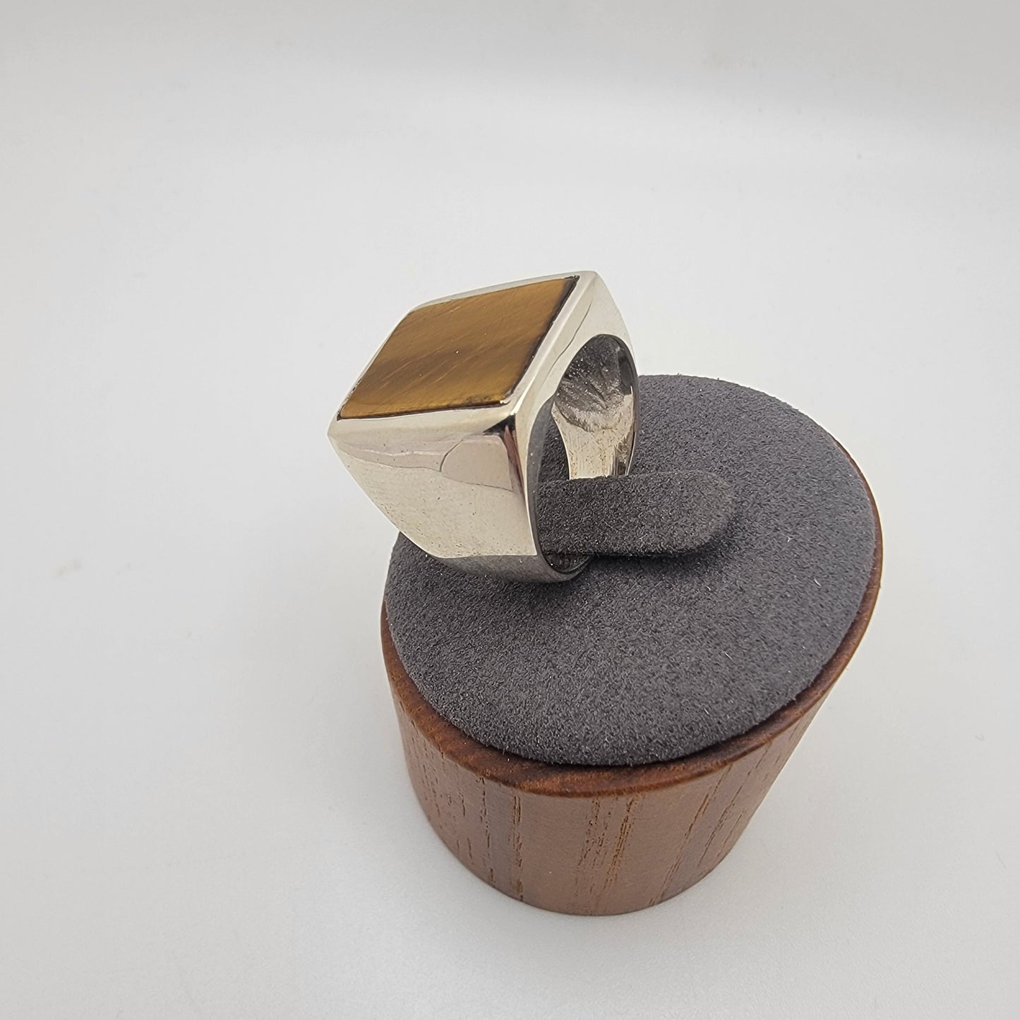 Silver ring with rectangular tiger's eye cabochon in grey and wooden stand