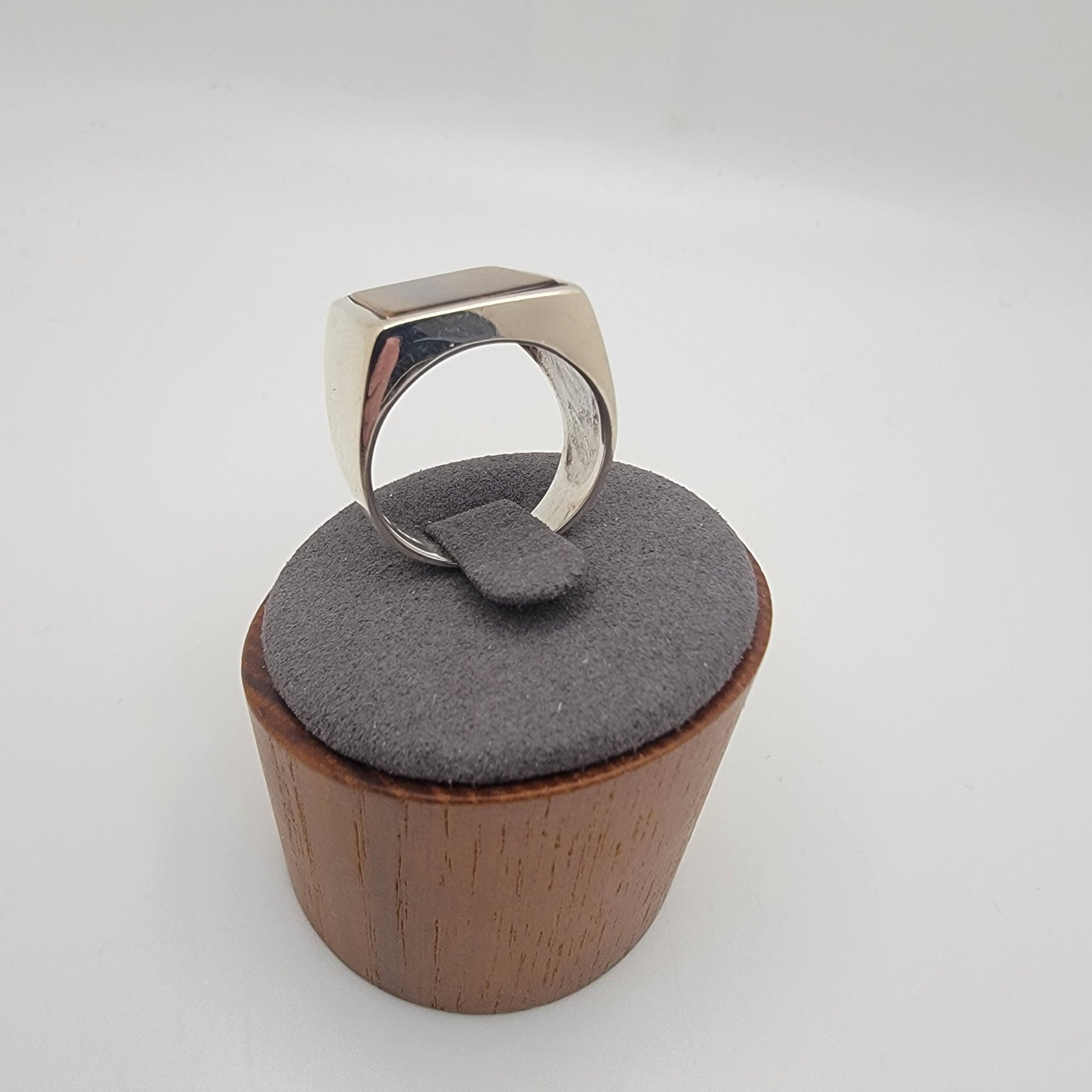 Silver ring with rectangular tiger's eye cabochon in grey and wooden stand