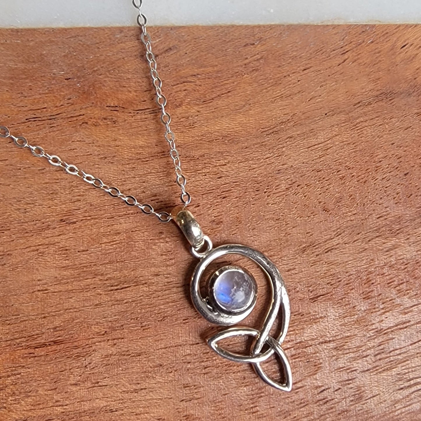Silver necklace with a moonstone pendant on a wooden surface
