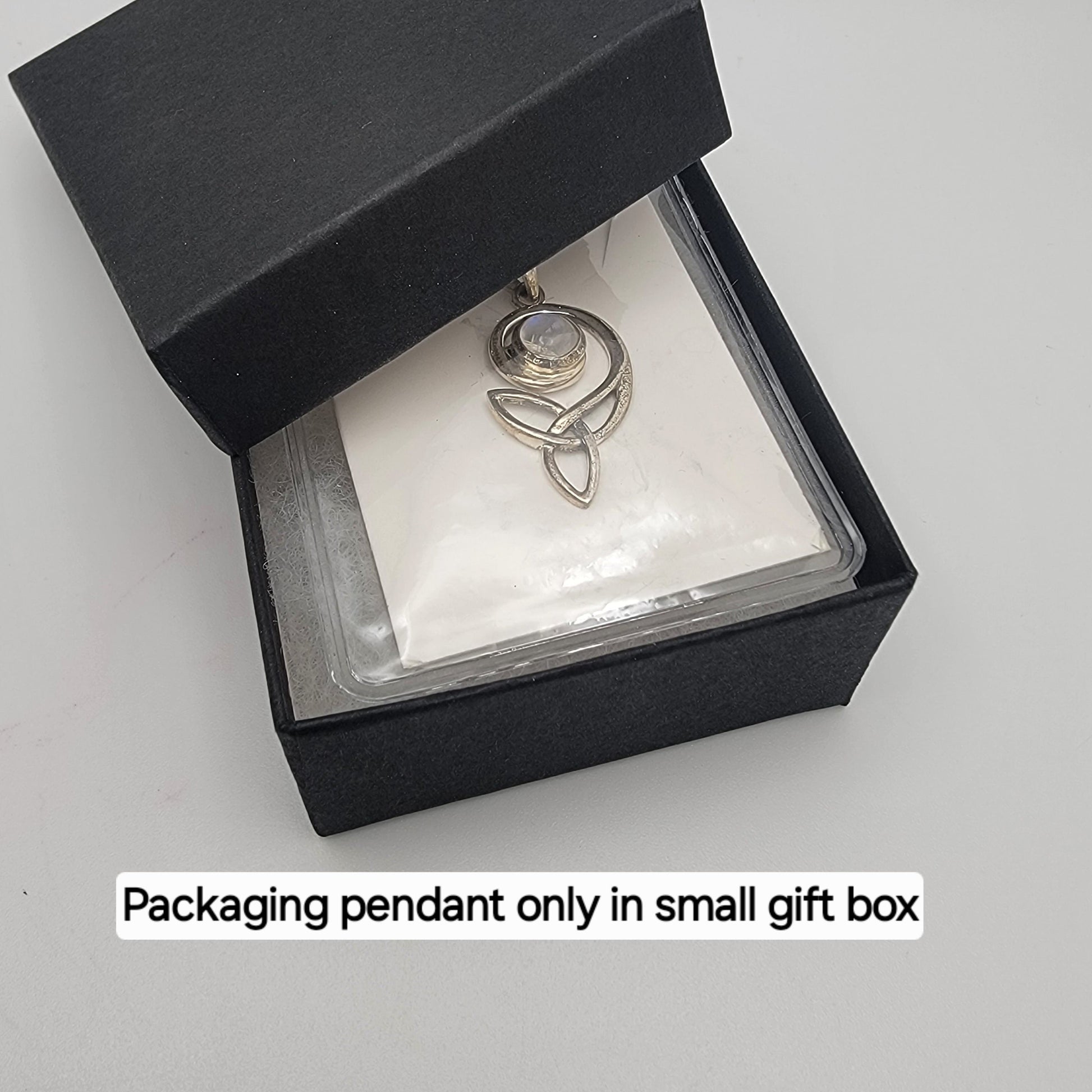 Silver pendant in a small black gift box on a white background