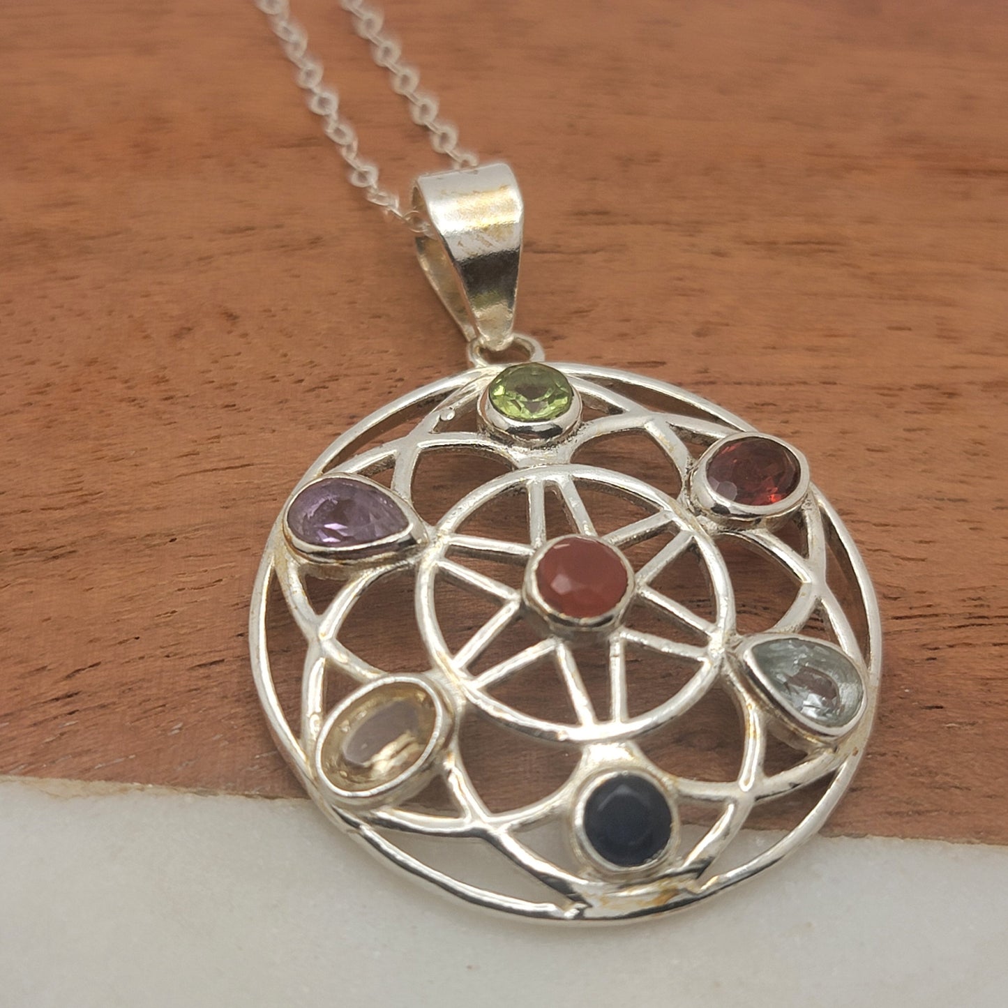 Silver pendant with gemstones on a wooden surface