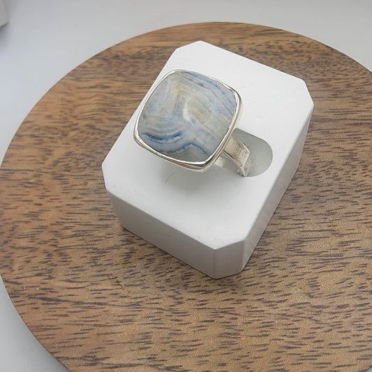 Silver ring with a blue and white scheelite marbled stone on a wooden stand.