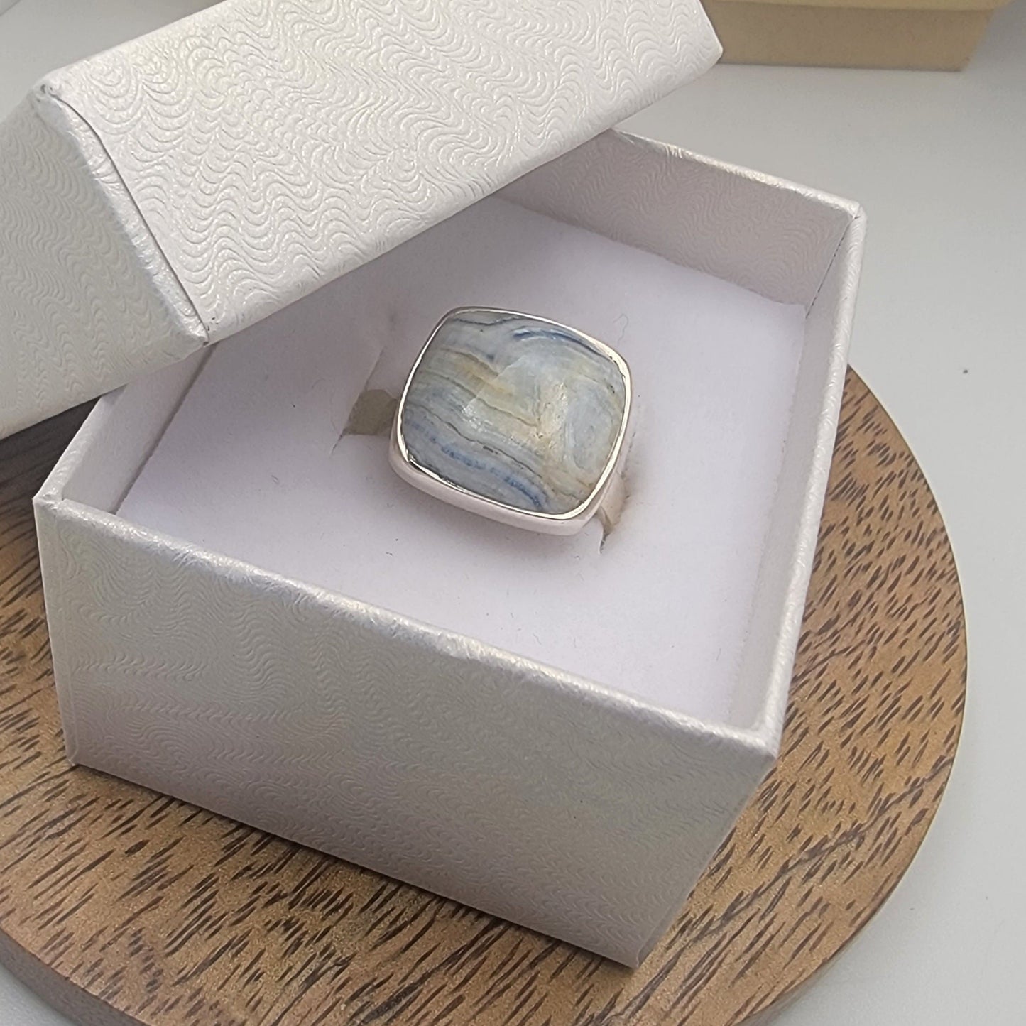 Silver ring with a stone in a white box on a wooden surface