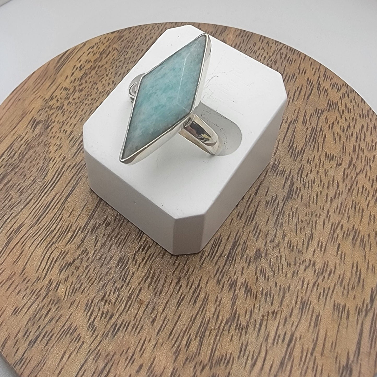 Ring with a larimar stone on a white stand against a wooden background