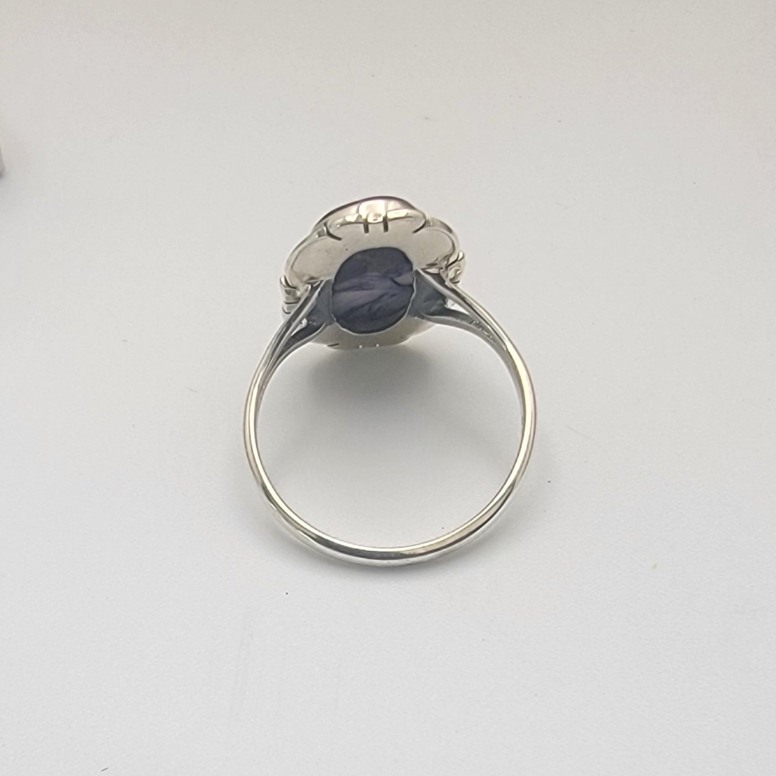 Sterling silver ring on a white surface with a gray textured object in the background