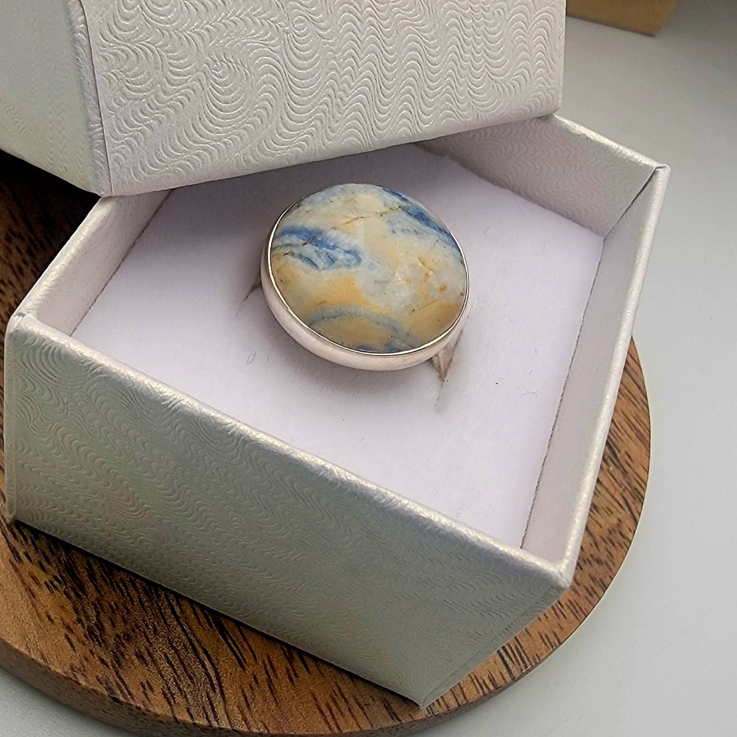 Marbled ring in a white jewelry box on a wooden surface