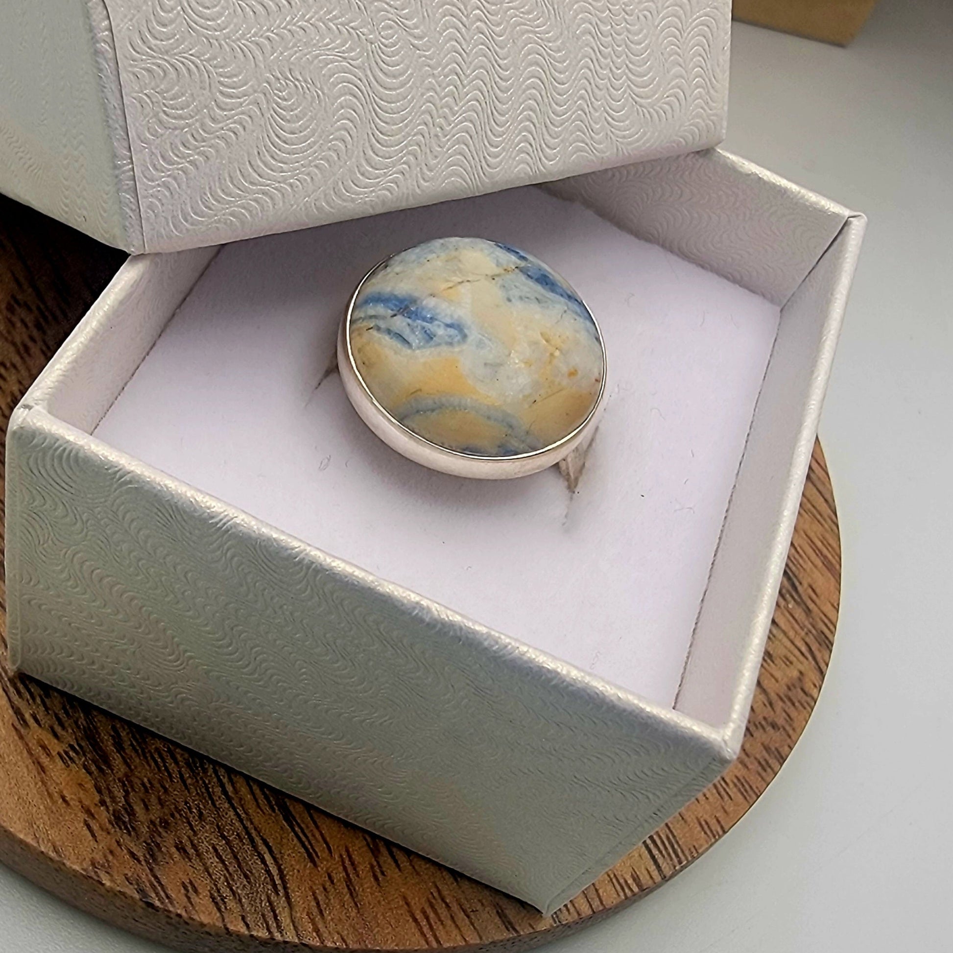 Marbled ring in a white jewelry box on a wooden surface