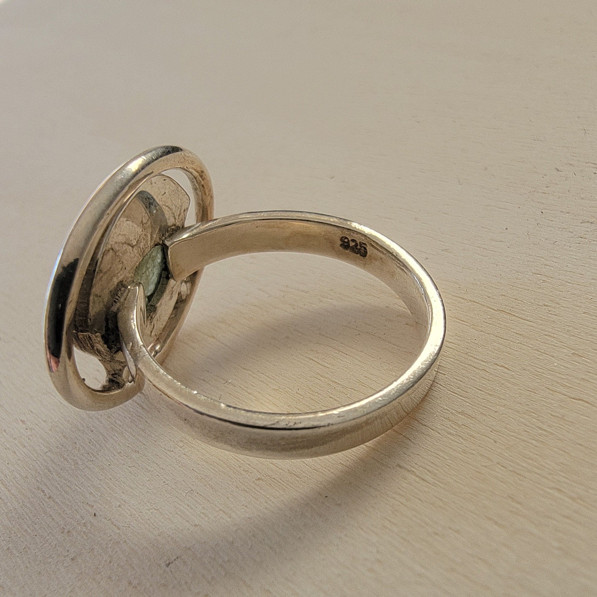 Silver ring on a light wooden surface