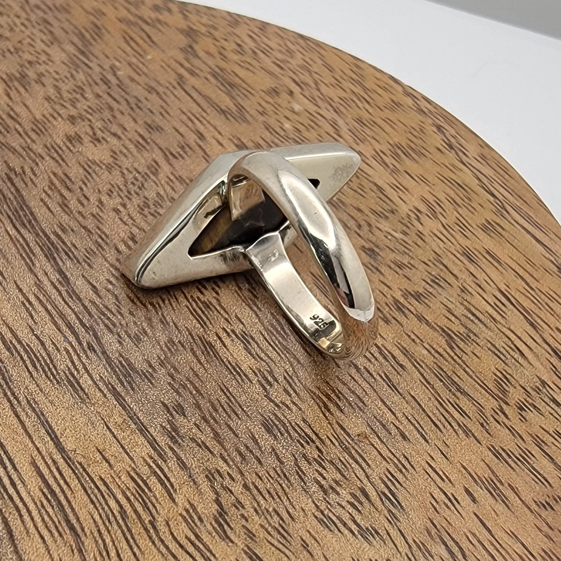 Sterling silver ring on a wooden surface with a neutral background